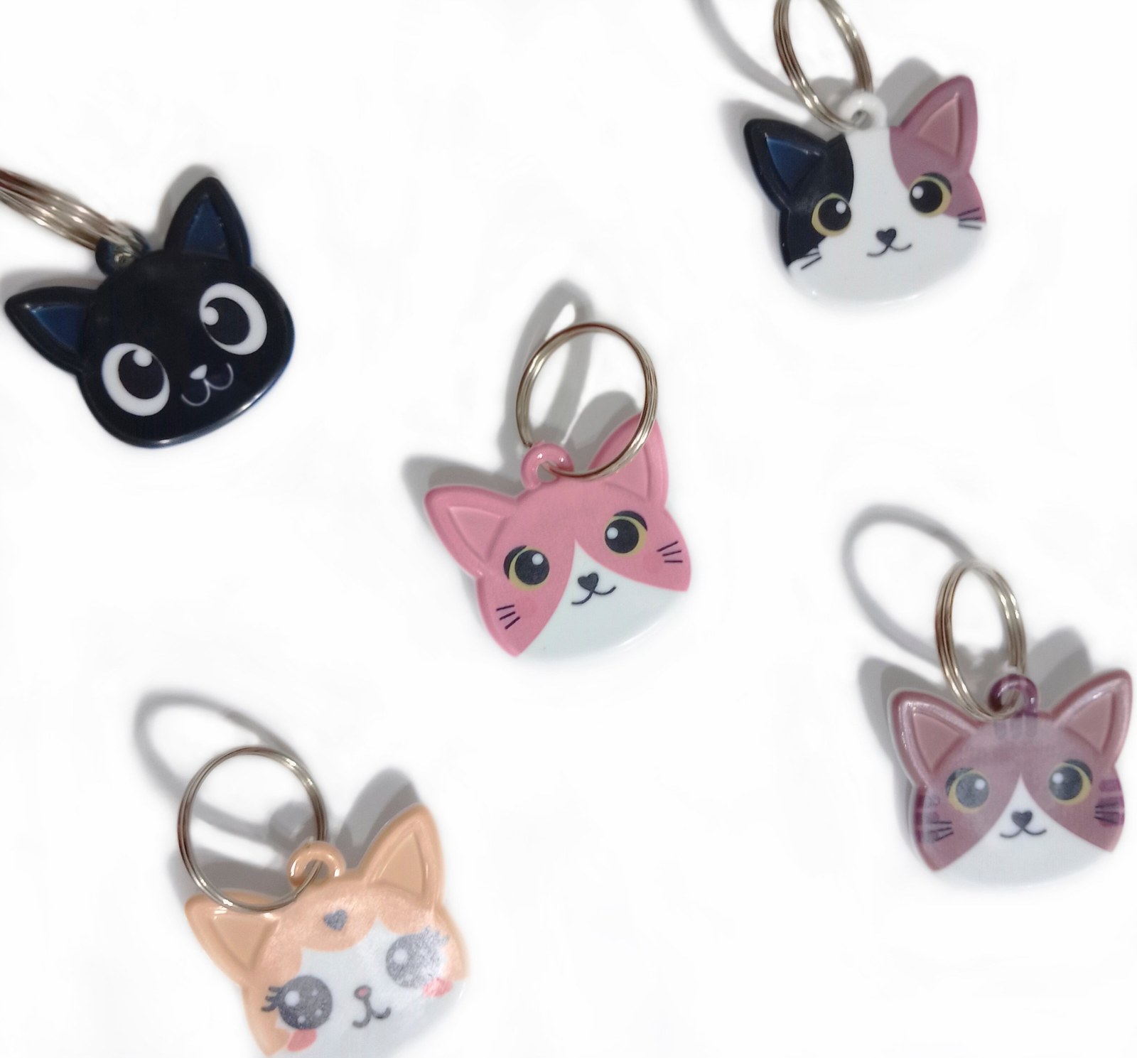 Chapitas identificatorias con forma de carita de gato en distintos colores y diseños